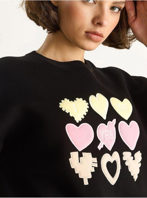 Felpa girocollo relaxed fit con applicazioni a patch a cuore lucci - Kiabi Felpa girocollo relaxed fit con applicazioni a patch a cuore lucci - Kiabi